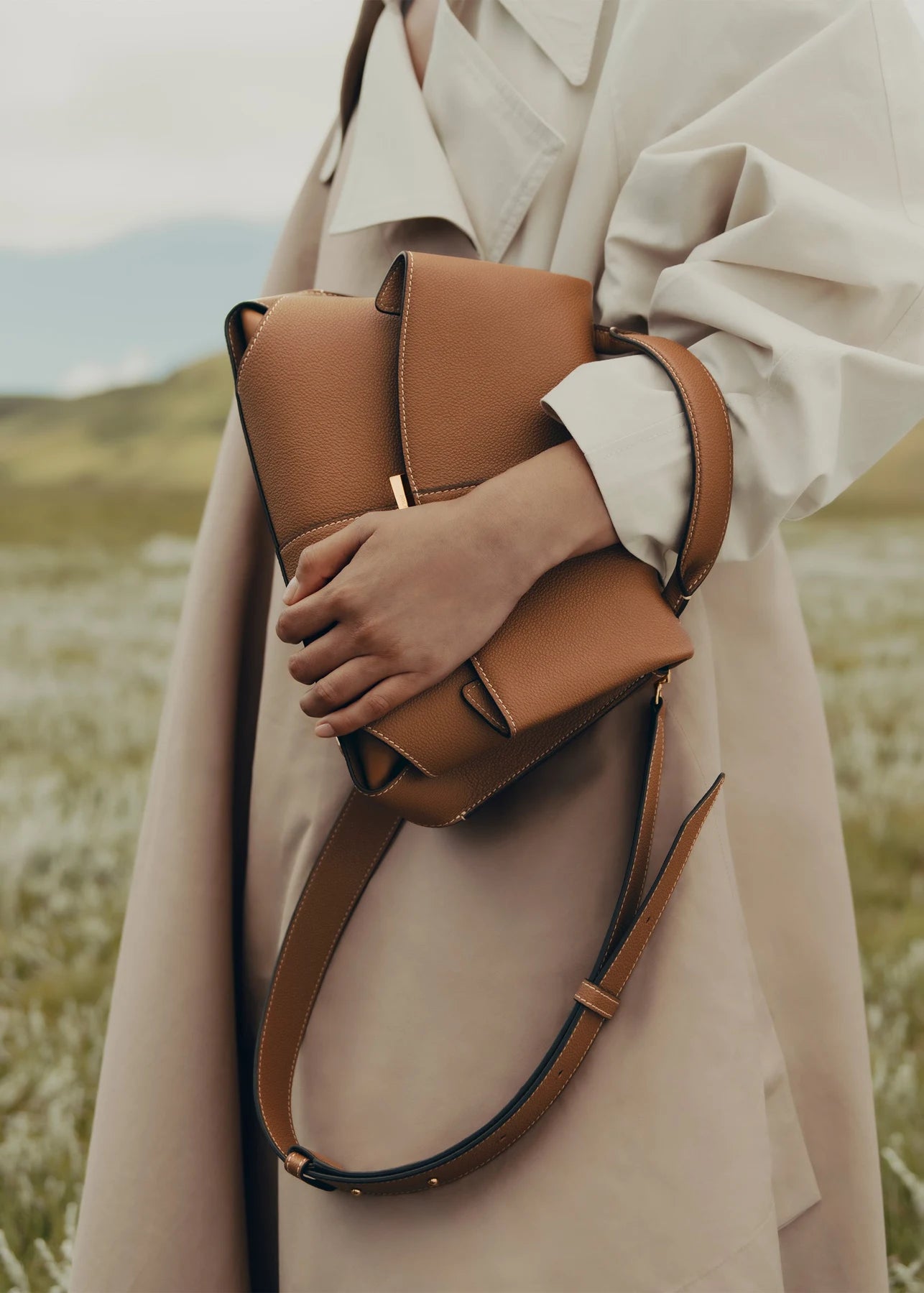 Close-up of a camel handbag with a cream outfit